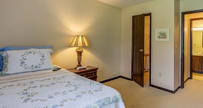 Brightly lit private resident room with a bed and lamp