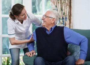 Arcadia of Crofton II, Nursing Home in Gambrills, MD — Caregiver assisting a smiling senior man in a living room