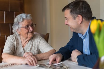 An elderly woman and a man looking at photos together