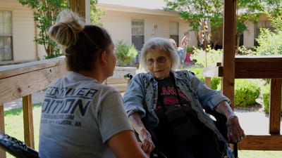 A resident and staff member engaged in conversation outdoors