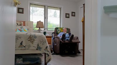 A resident relaxing in a comfortable chair in their room