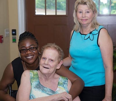 Staff members and a resident smiling together