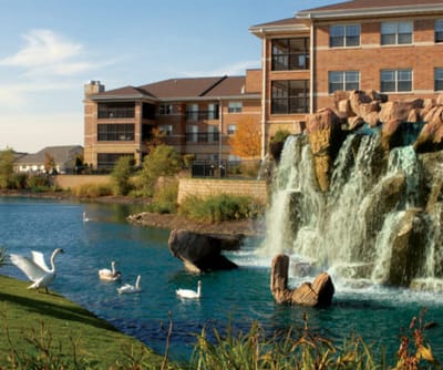 Exterior view of a senior living facility by a pond