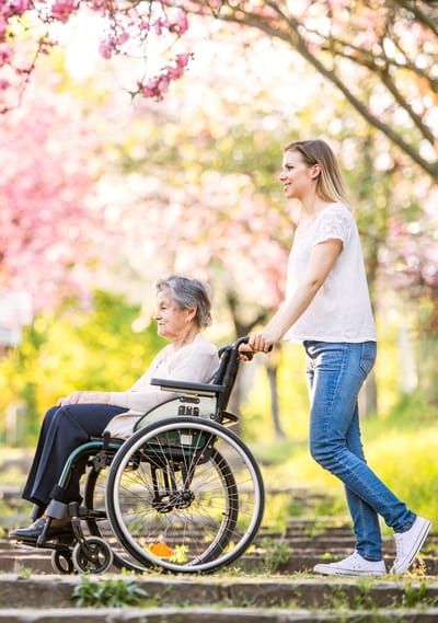 Woman pushing a resident in a wheelchair outdoors