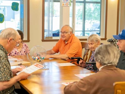 Residents playing bingo around a table in a communal space
