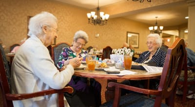 Three residents enjoying meals in a dining area