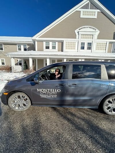 A resident and staff member in a van outside Montello Heights