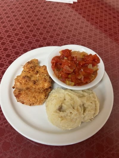 A plated meal featuring chicken, mashed potatoes, and salsa