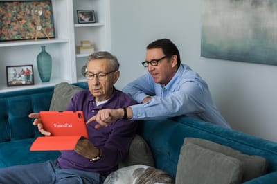Senior man engaged with staff member using tablet