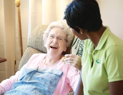 Caregiver laughing with senior resident in a warm indoor setting