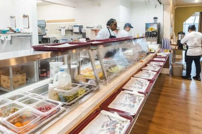 Dining area with staff preparing food at a buffet station