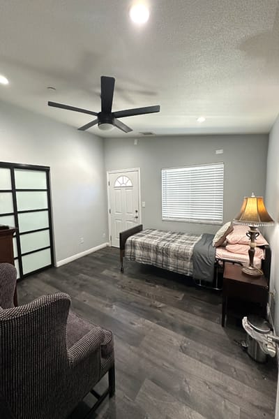 A well-furnished private resident room with a bed and seating area