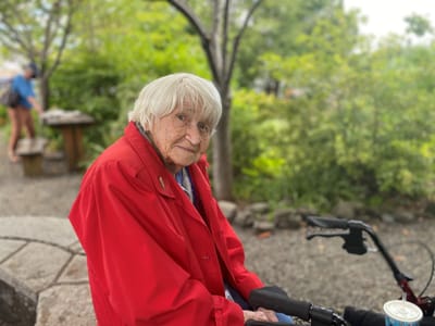 Elderly resident in a red jacket outdoors in a garden