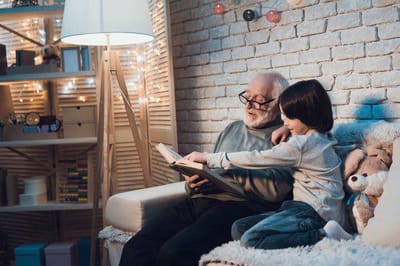 An elderly man reading with a young child