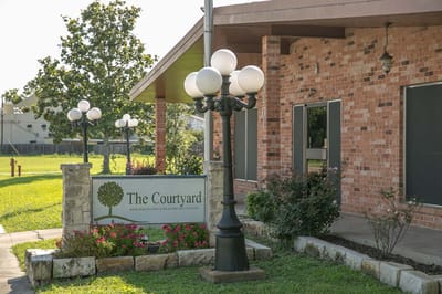 Exterior view of The Courtyard facility with landscaping.