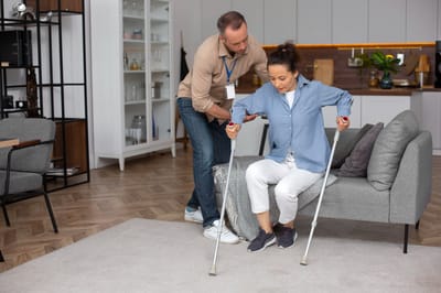 Caregiver assisting a resident with crutches.