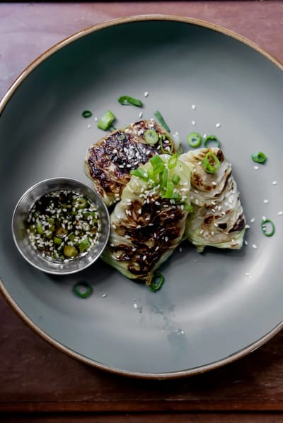 Grilled cabbage with dipping sauce on a plate