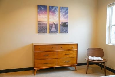 A modern interior room setup with a dresser and art on the wall