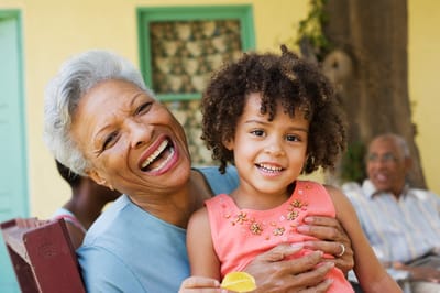 An elderly woman and a young girl laughing together outdoors
