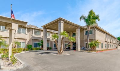 Exterior view of a senior living facility with palm trees