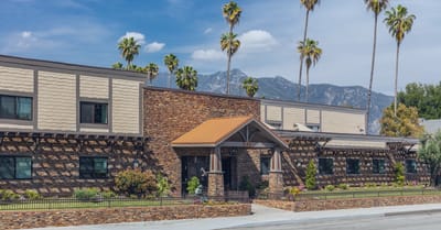 Exterior view of a senior living facility surrounded by palm trees