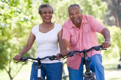 Happy seniors riding bicycles in a park.