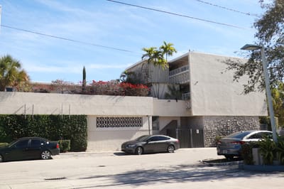 Exterior view of a senior living facility with cars parked