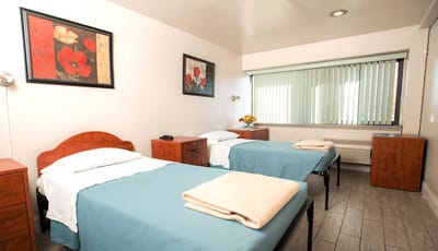 A cozy resident room with two beds and floral decor