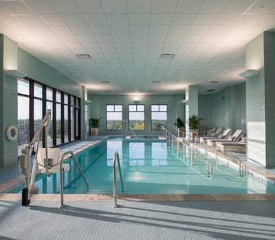 Indoor swimming pool with accessibility features and lounge chairs