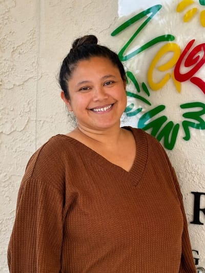 Staff member smiling in front of facility signage