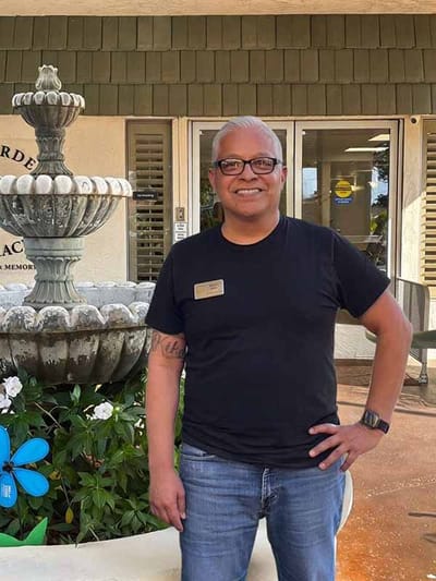 Staff member smiling near a garden fountain.