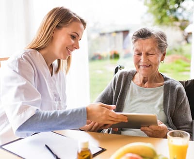 Caregiver assisting elderly resident with a tablet