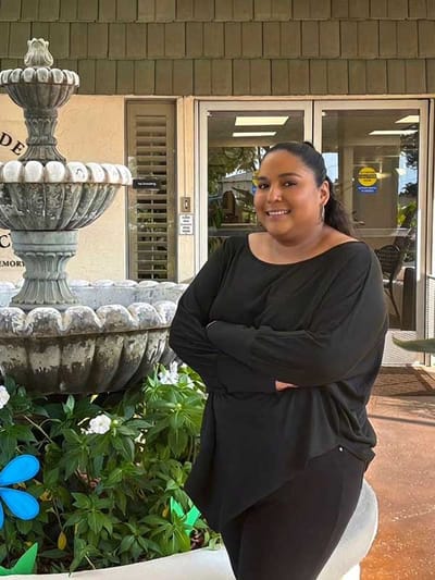 Staff member poses by a fountain in the garden.