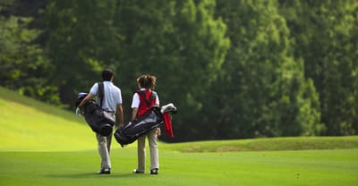 Two golfers walking on a green golf course