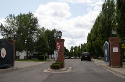 Entrance gate of a senior living facility with trees along the road