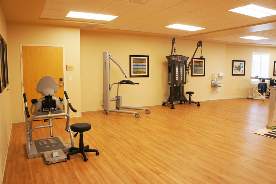 Rehabilitation gym with exercise equipment and wooden flooring