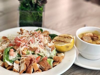 A plate of Caesar salad with chicken and soup