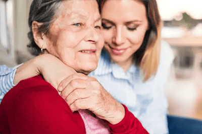 A young woman embracing an elderly woman indoors