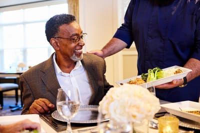 Resident enjoying a meal with staff assistance