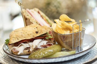 A gourmet sandwich with chips and pickles on a plate
