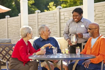 Residents enjoying refreshments outdoors with staff