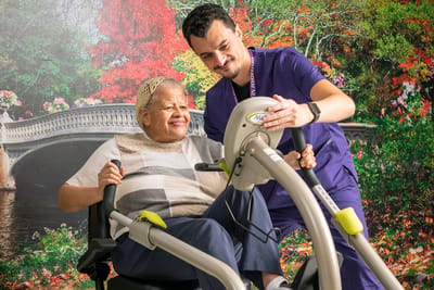 A staff member assisting a resident with exercise equipment