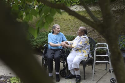 Two residents sitting together in a garden area