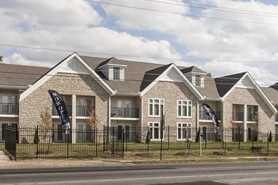 Exterior view of a senior living facility with gardens and signage