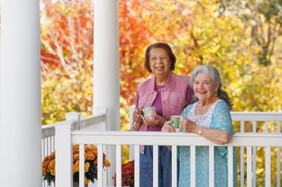Two residents enjoying drinks on a balcony in autumn