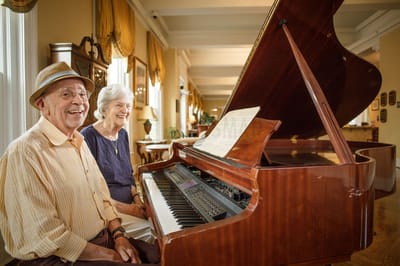 Two residents enjoying music at a piano in a common area