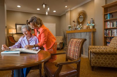 Resident and staff looking at a photo album in a cozy common area