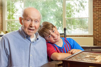 An elderly man and a young boy enjoying time together indoors
