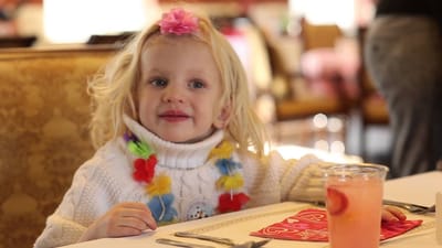 A young girl smiling at a dining table