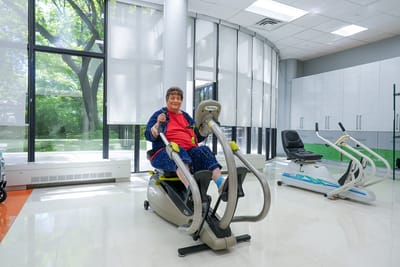 Resident using exercise equipment in a bright activity room